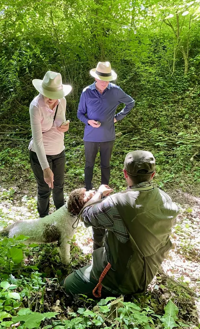 Guests accompanied by a truffle hunter and his dog among the trees of the reserve